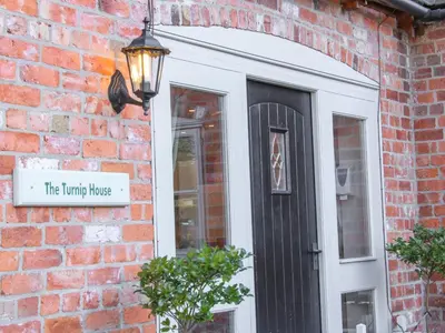 a black door with a sign on a brick building at The Turnip House in Acton Scott