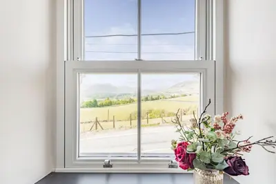 a vase of flowers in a window with a view at 2 Bryn Tirion in Tanygrisiau