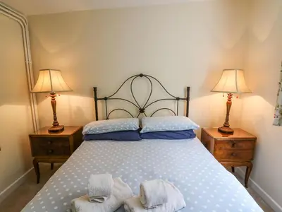a bedroom with a large bed with two lamps at Salmon Cottage in Llanwrthwl