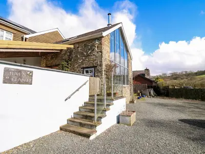 a stone house with glass walls and stairs at The Barn at Glanoer in Bettws Disserth