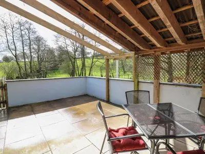 a patio with a table and chairs on a balcony at The Barn at Glanoer in Bettws Disserth