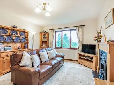 a living room with a brown leather couch and a tv at Llety Nest in Llanfachreth