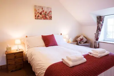 a bedroom with a large white bed and a window at Stabal Cottage in Cross Foxes