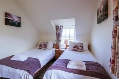 two twin beds in a room with a window at Stabal Cottage in Cross Foxes
