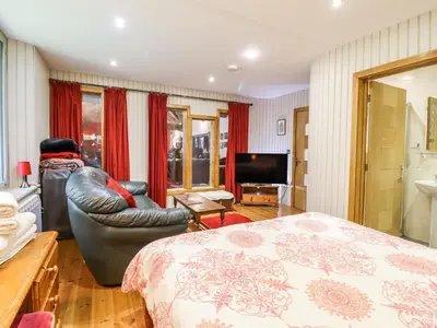 a bedroom with a bed and a chair and a television at St Mary's in Tal-y-llyn