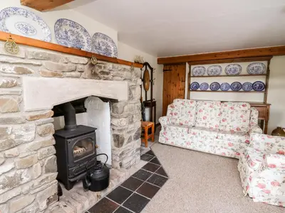 a living room with a stone fireplace and a couch at Llety'r Wennol in Llanycrwys