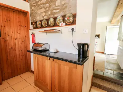 a kitchen with wooden cabinets and a counter top at Llety'r Wennol in Llanycrwys