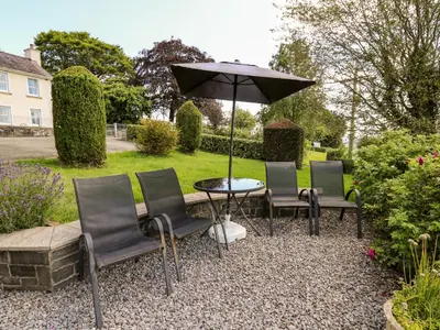 a table and chairs with an umbrella in a garden at Llety'r Wennol in Llanycrwys