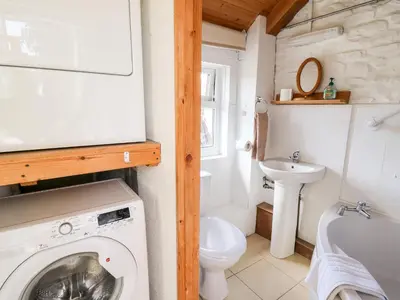 a bathroom with a washing machine and a sink at Llety'r Wennol in Llanycrwys