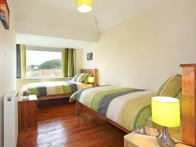 a bedroom with two beds and a table with a lamp at Trysor Y Mor in Borth
