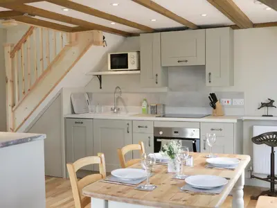 a kitchen with a wooden table with chairs and a kitchen with white cabinets at Bicton Lodge in Clun