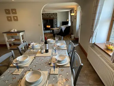 a dining room with a table set with plates and glasses at Tangaer Cottage in Cellan