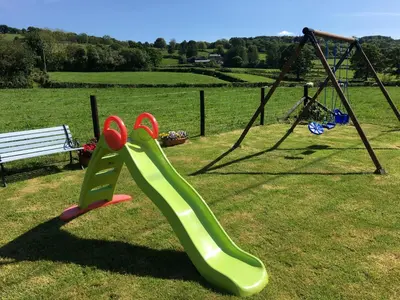 a playground with a slide and a swing at Tangaer Cottage in Cellan