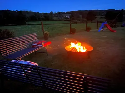 a fire pit in a yard with a bench and a playground at Tangaer Cottage in Cellan