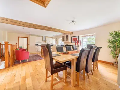 a kitchen and dining room with a wooden table and chairs at Old Rectory Cottages in Aberhafesp