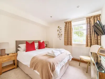 a bedroom with a bed with red pillows and a window at Old Rectory Cottages in Aberhafesp