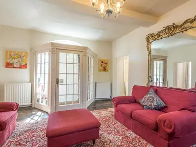 a living room with a red couch and a mirror at The Old Schoolhouse and Cottage in Bishops Castle