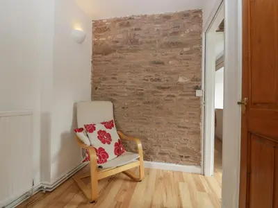 a chair sitting in a room with a brick wall at Wheelbarrow Cottage in Stoke Prior