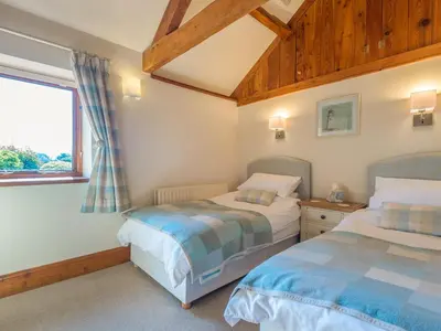 two beds in a room with a window at Parrs Meadow Cottage in Pitchford