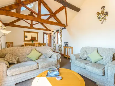 a living room with two couches and a table at Parrs Meadow Cottage in Pitchford