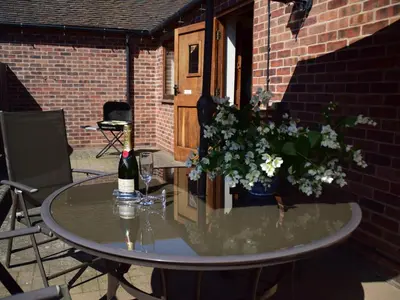 a table with a bottle of wine and flowers on it at Parrs Meadow Cottage in Pitchford