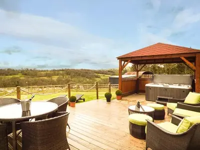 a wooden deck with tables and chairs and a grill at Cwmcelyn in Nantmel