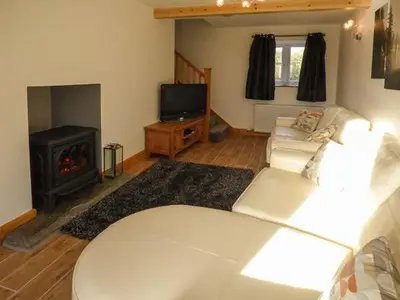a living room with a white couch and a fireplace at Cwmcelyn in Nantmel
