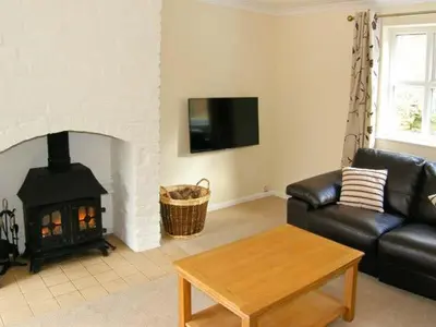 a living room with a black leather couch and a fireplace at Forestry Cottage in Pale