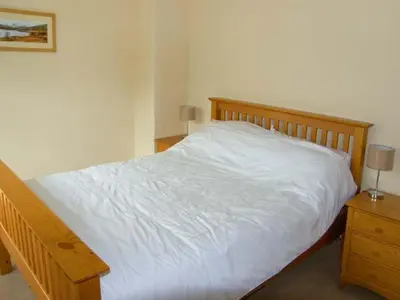 a bedroom with a white bed and a night stand at Forestry Cottage in Pale