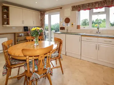 a kitchen with a wooden table with chairs and a vase of flowers at Tregarthens in Church Stretton