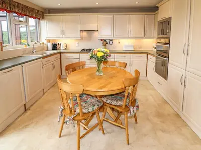 a kitchen with a wooden table with chairs and a vase of flowers at Tregarthens in Church Stretton
