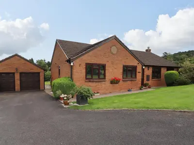 a brick house with a garage and a driveway at Tregarthens in Church Stretton