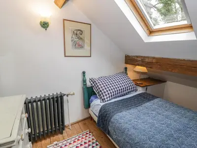 a small attic bedroom with a bed and a window at Beudy Dolpebyll in Llangadfan