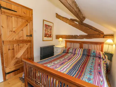a bedroom with a bed and a wooden door at Beudy Dolpebyll in Llangadfan
