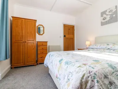 a bedroom with a bed and a wooden cabinet at Bron Aber in Arthog