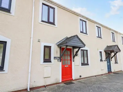 a building with a red door on a street at Ty'r Heulwen in Aberdyfi