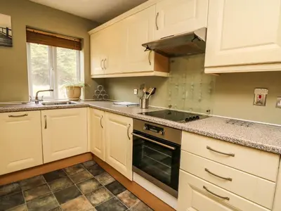 a kitchen with white cabinets and a stove top oven at Ty'r Heulwen in Aberdyfi