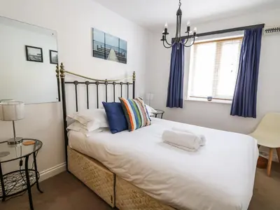 a bedroom with a large white bed with blue curtains at Ty'r Heulwen in Aberdyfi