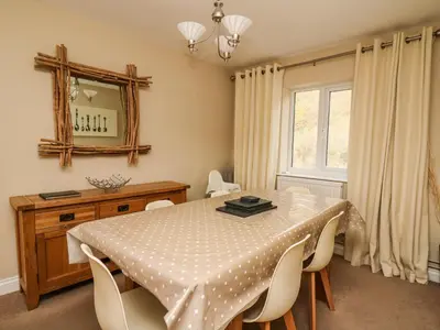 a dining room with a table and chairs and a mirror at Ty'r Heulwen in Aberdyfi