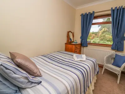 a bedroom with a bed with blue curtains and a window at Drainbyrion Farm House in Van