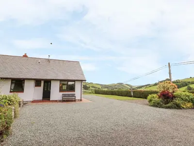 a small white house with a gravel driveway at Drainbyrion Farm House in Van