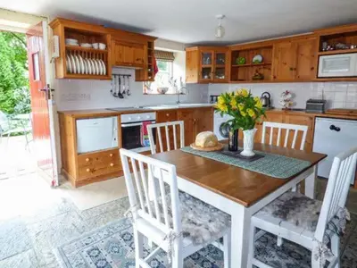 a kitchen with a wooden table with chairs and a tableasteryasteryasteryasteryastery at Crud-y-Barcud in Pumpsaint