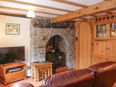 a living room with a couch and a stone fireplace at Tuc - Tin in Clun