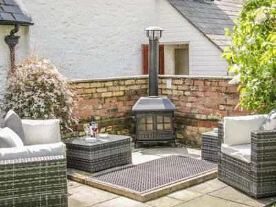 a patio with a brick wall and a stove at Penymaes in Chirk