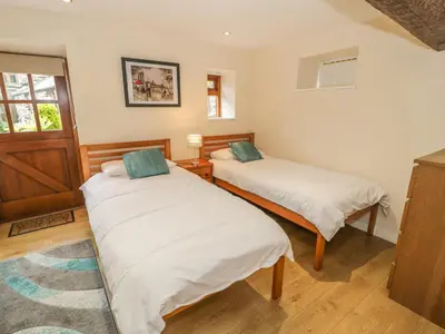 two twin beds in a room with a window at Hendoll Cottage 1 in Fairbourne