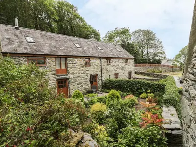 an old stone cottage with a garden in front of it at Hendoll Cottage 1 in Fairbourne