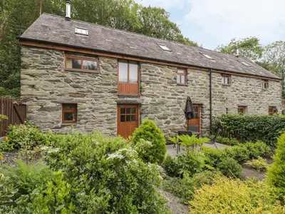 a stone cottage in the middle of a garden at Hendoll Cottage 1 in Fairbourne
