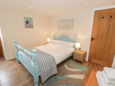 a bedroom with a blue bed and a wooden door at Hendoll Cottage 2 in Fairbourne