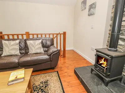 a living room with a couch and a wood stove at Hendoll Cottage 2 in Fairbourne