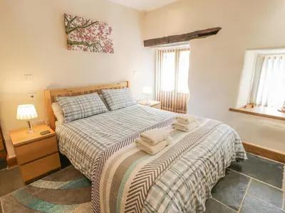 a bedroom with a bed with two towels on it at Hendoll Barn in Fairbourne